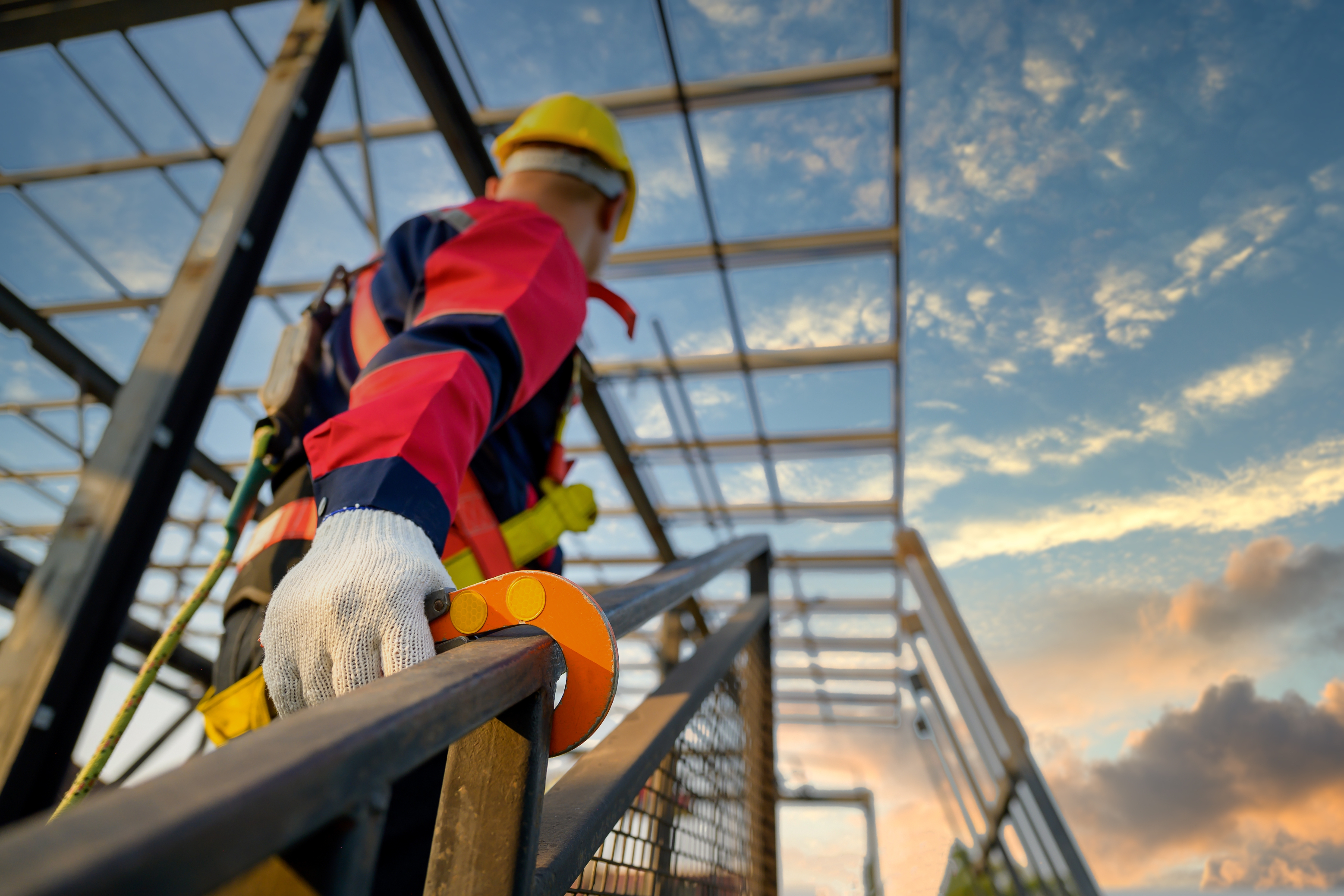 Construction worker climbing scaffolding at sunrise