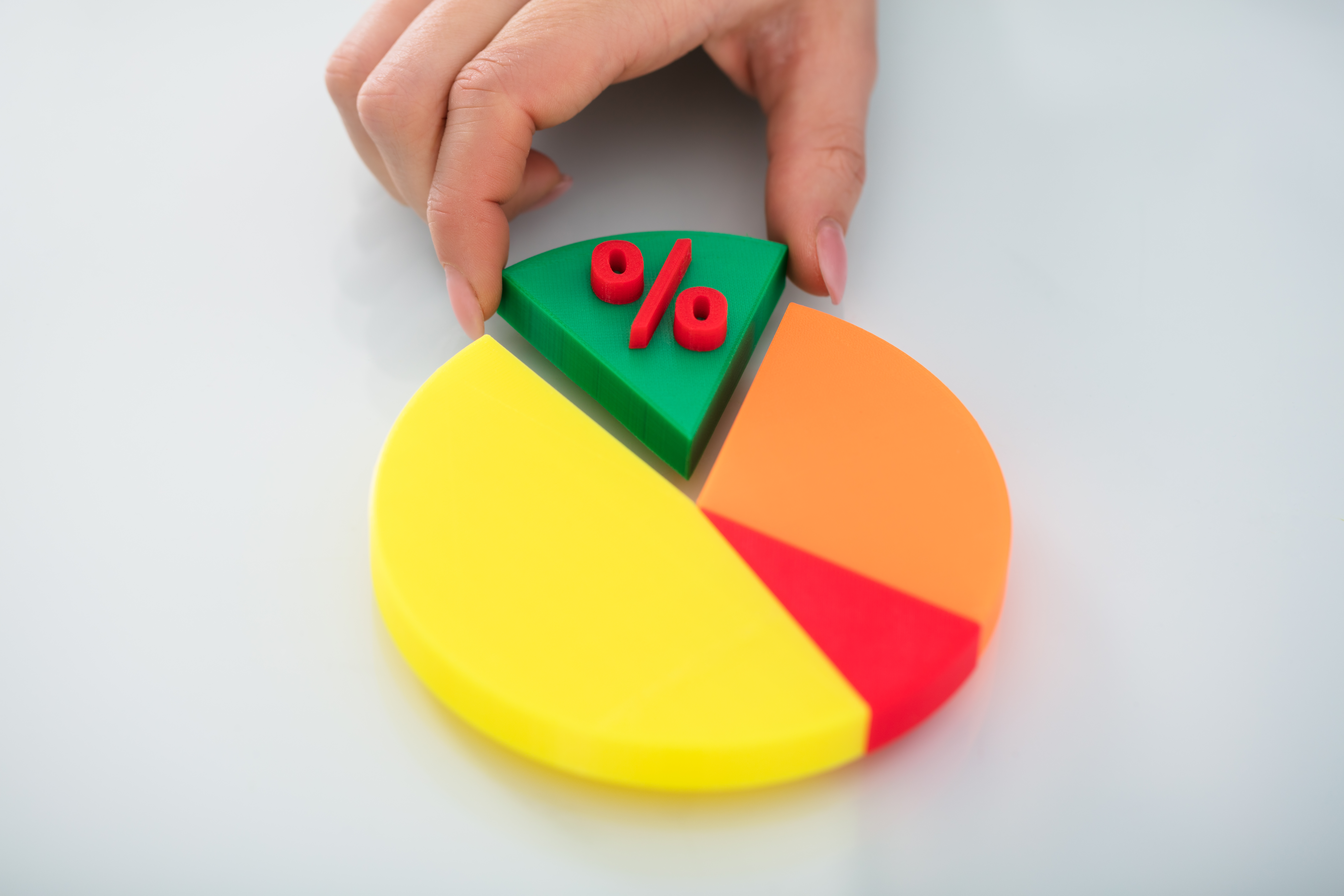 Hand placing a piece into a colourful pie chart