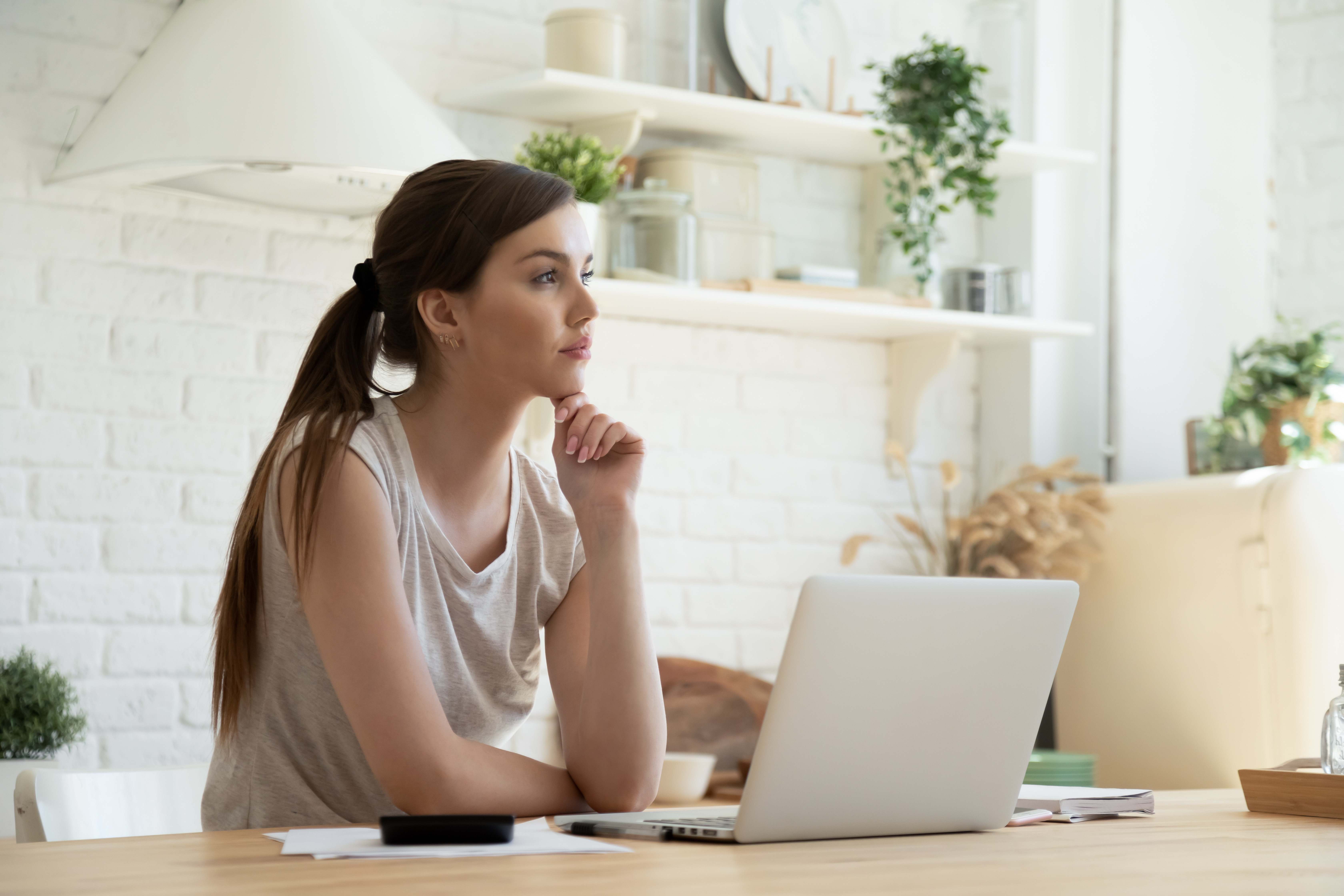 Employee sitting at a laptop, looking thoughtful and considering the future