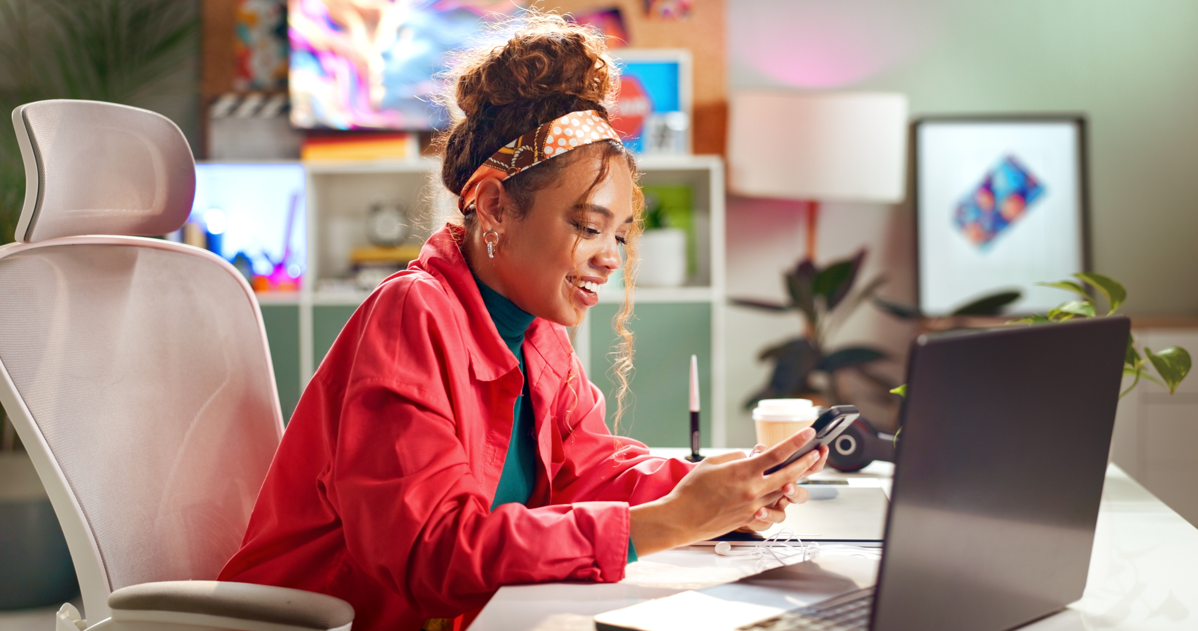 Young woman smiling at her phone at a creative desk